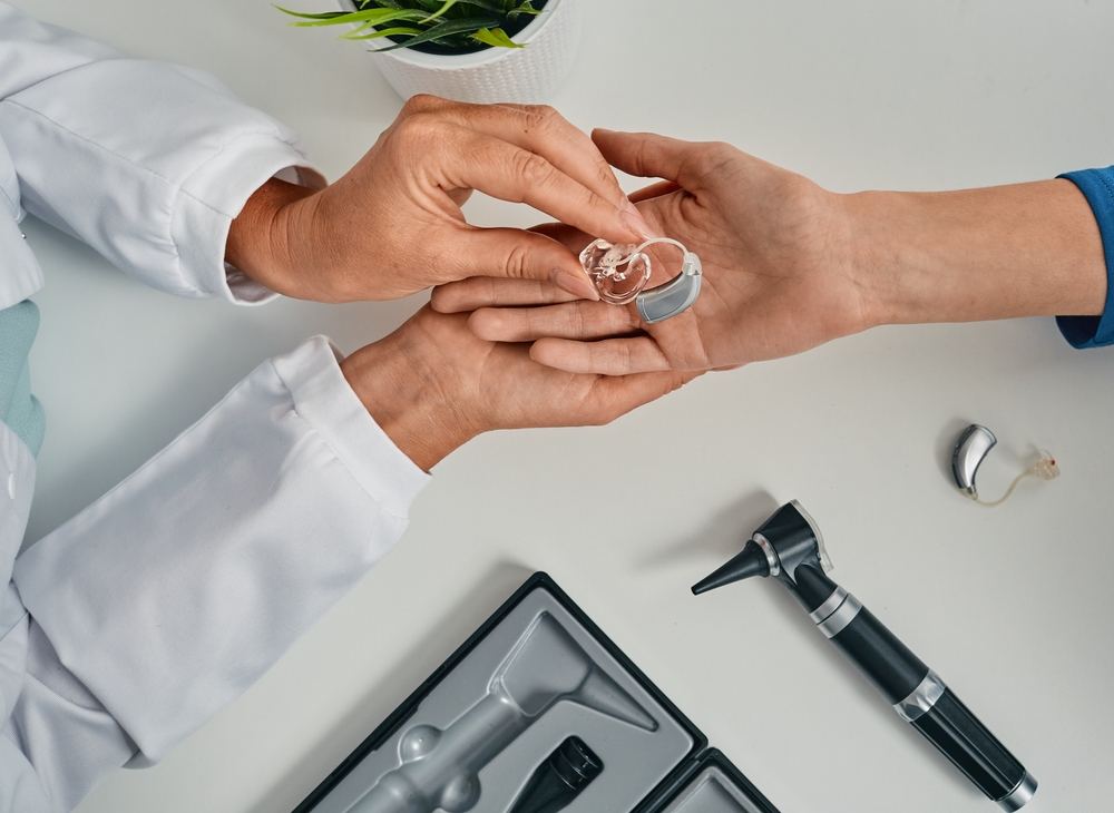 audiologist puts modern bte hearing aid in a patient's hand