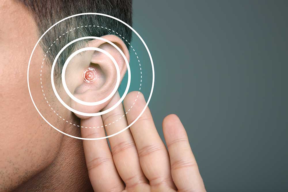 Man holding ear with hearing aid